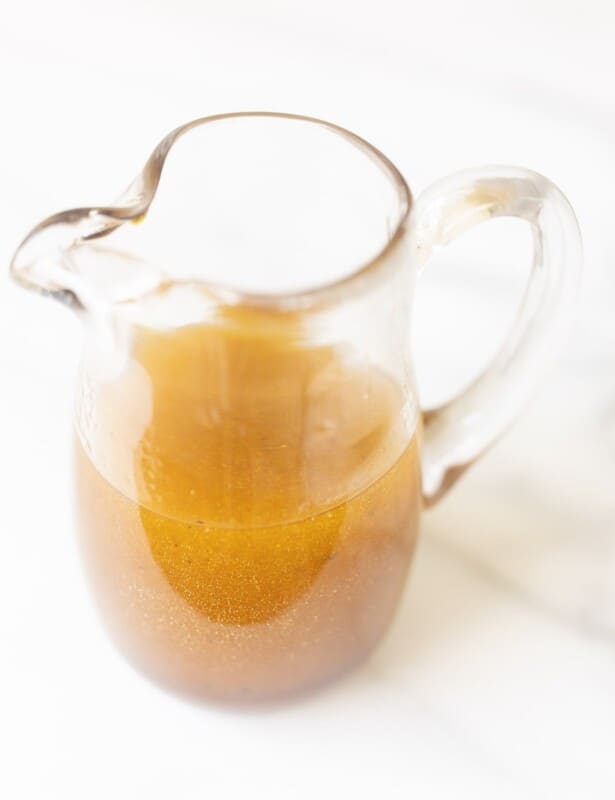 Balsamic vinaigrette in a clear pitcher on a marble surface.