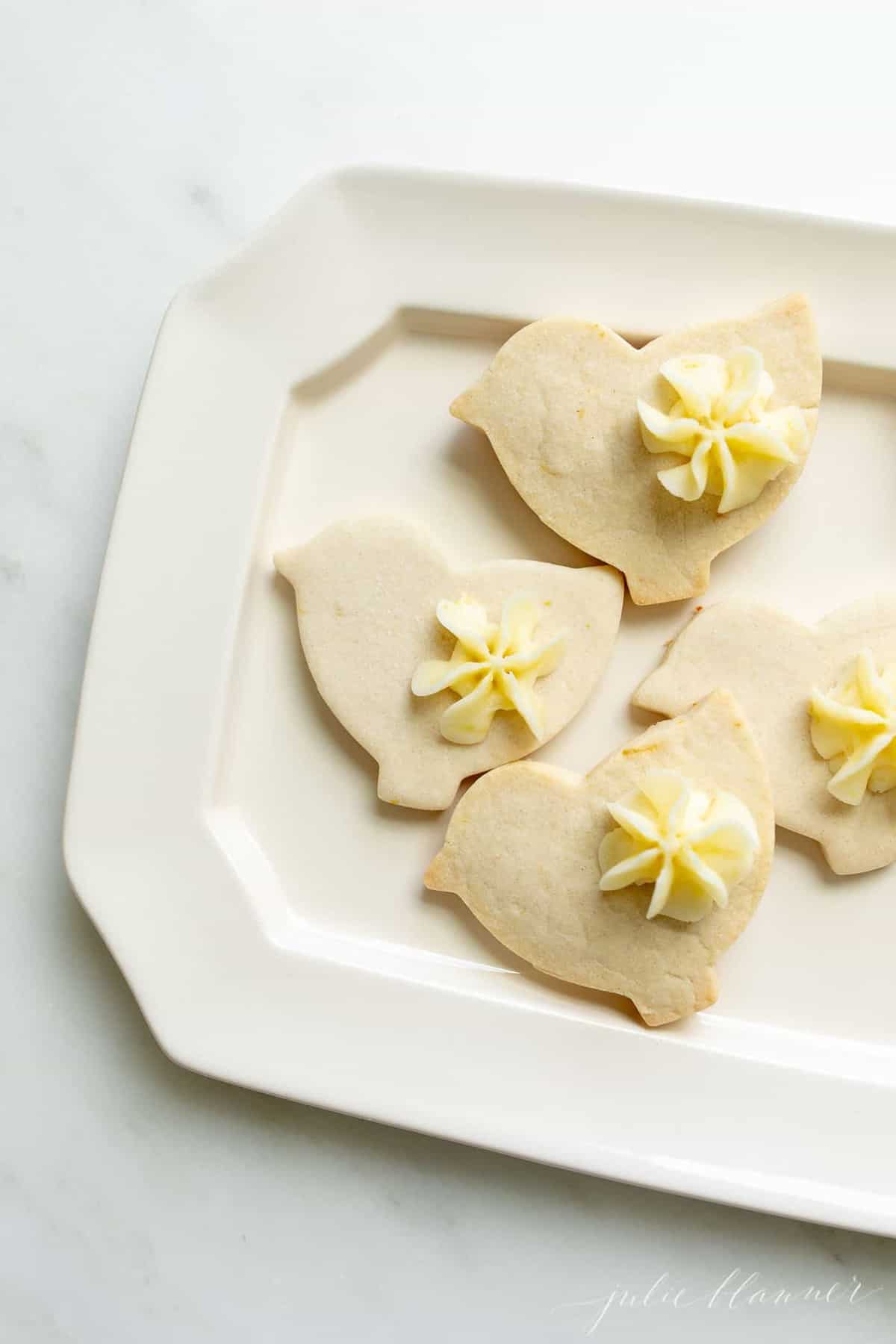 A white platter with lemon frosted cookies cutout as ducks.