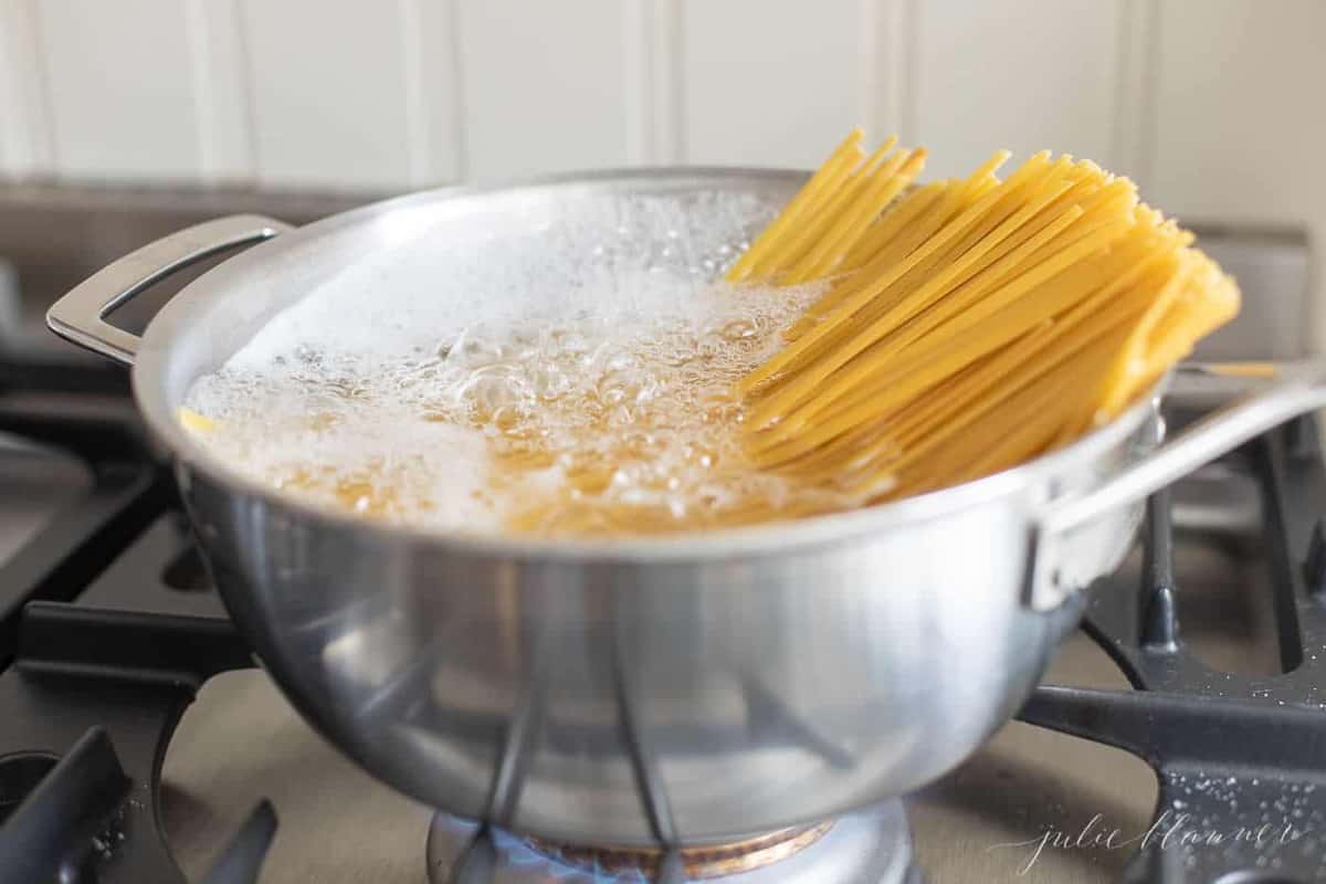 Fettuccine noodles in a pan full of boiling water.