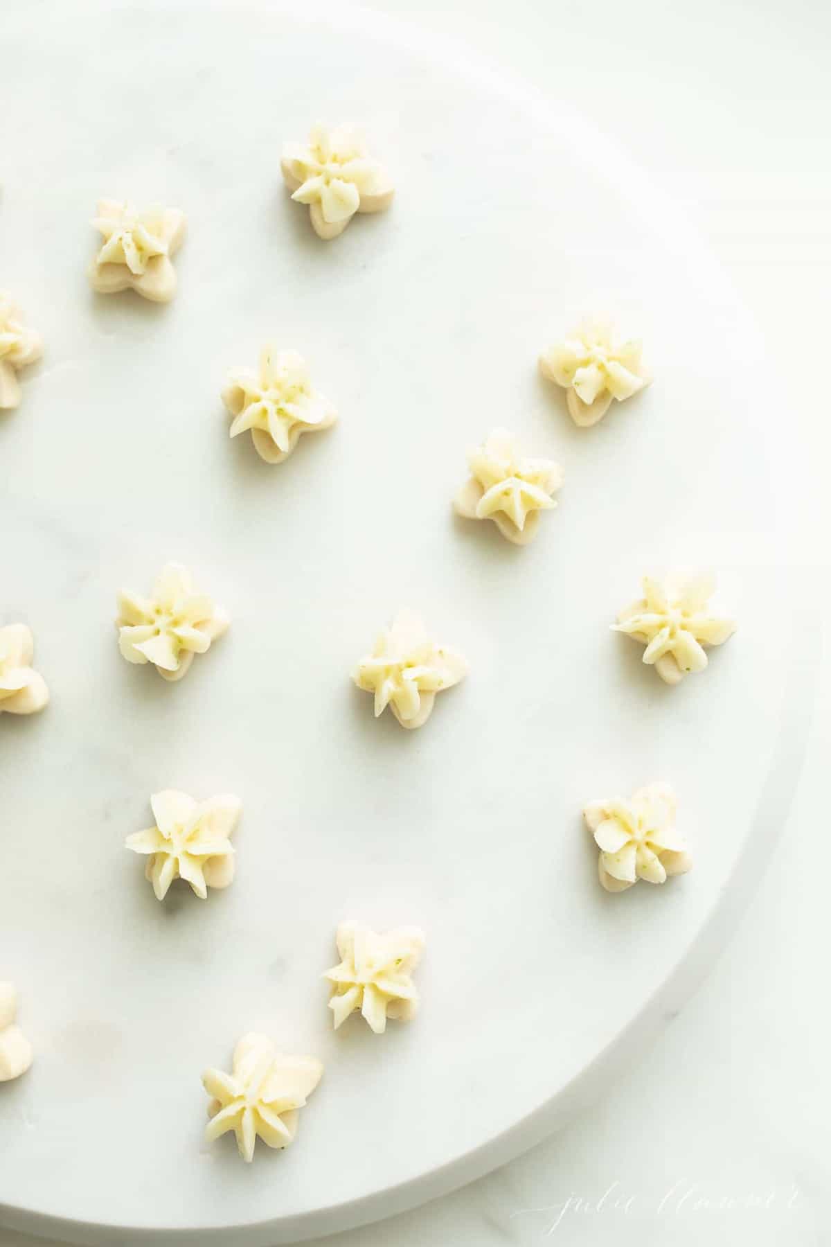 Tiny key lime cookies with frosting on a white surface.