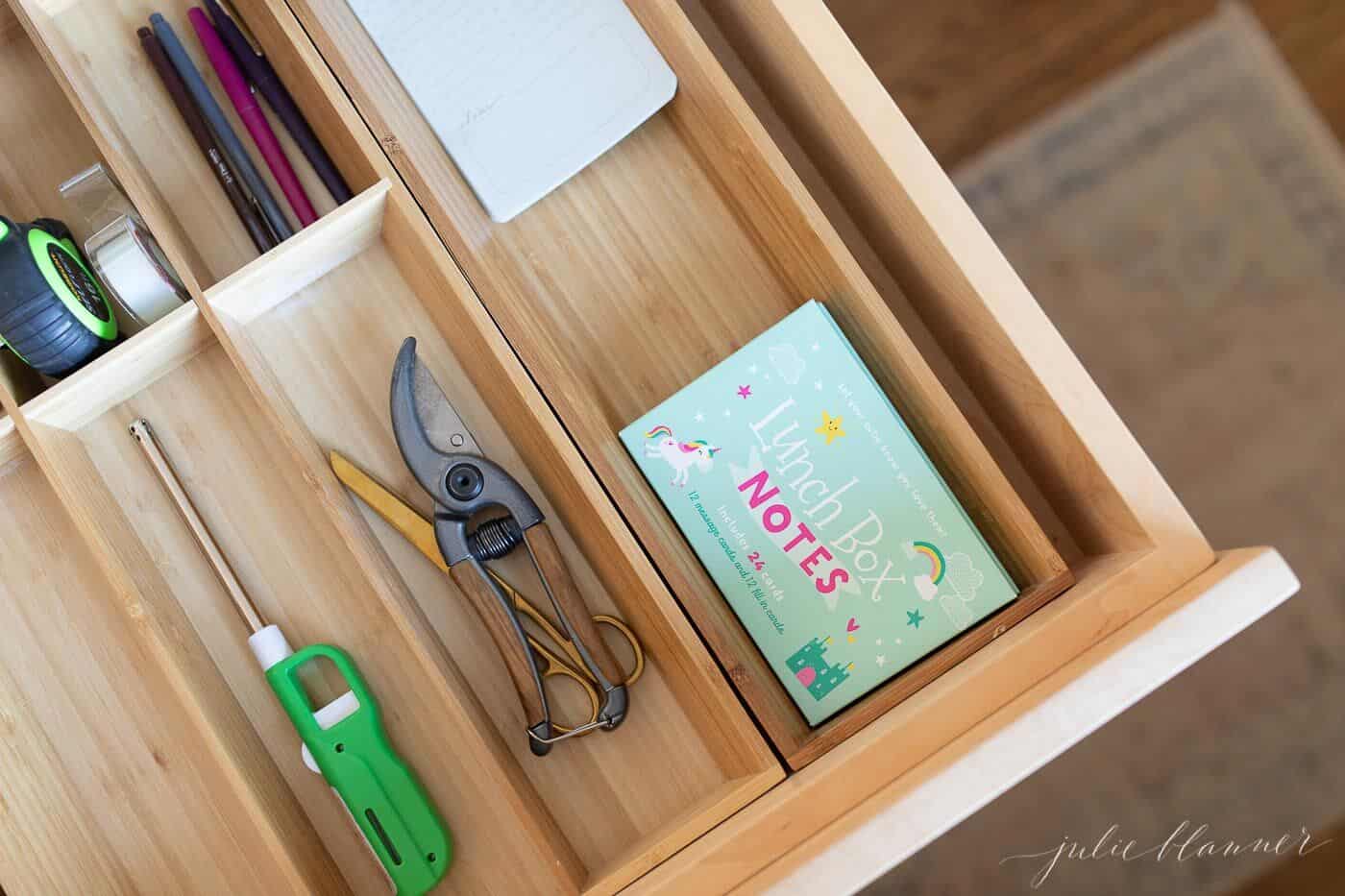 Wooden drawer inserts in a kitchen junk drawer.