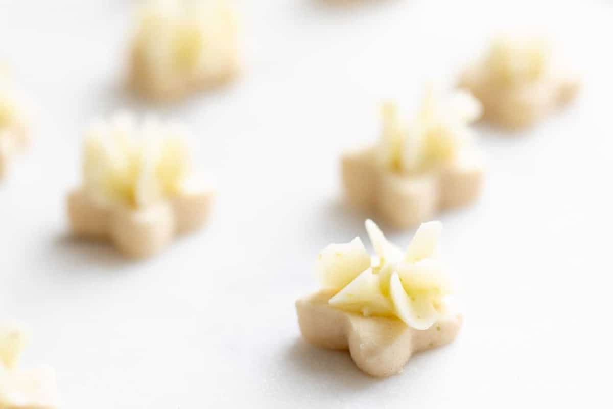 Tiny key lime cookies with frosting on a white surface.