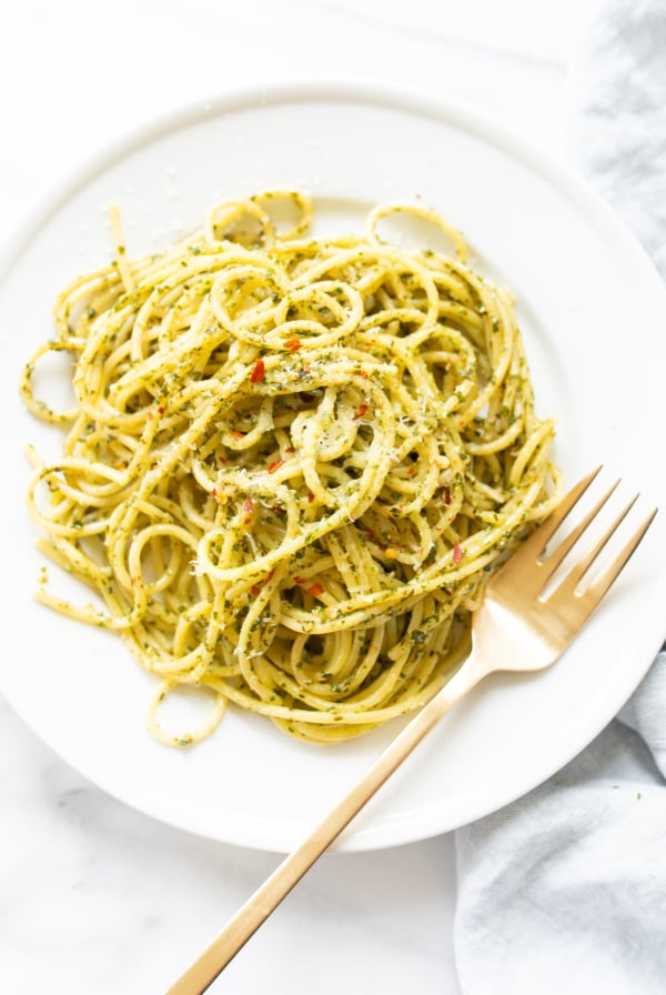 Pesto pasta recipe on a white plate with a fork.