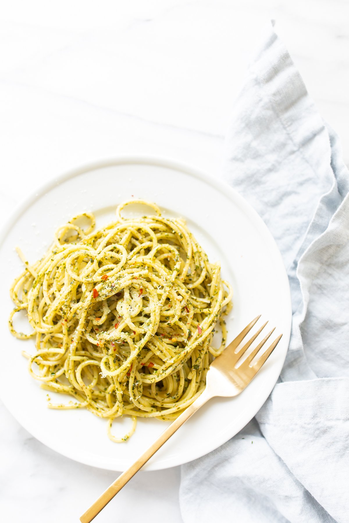 A tantalizing plate of pesto pasta with a fork on top, ready to be devoured.