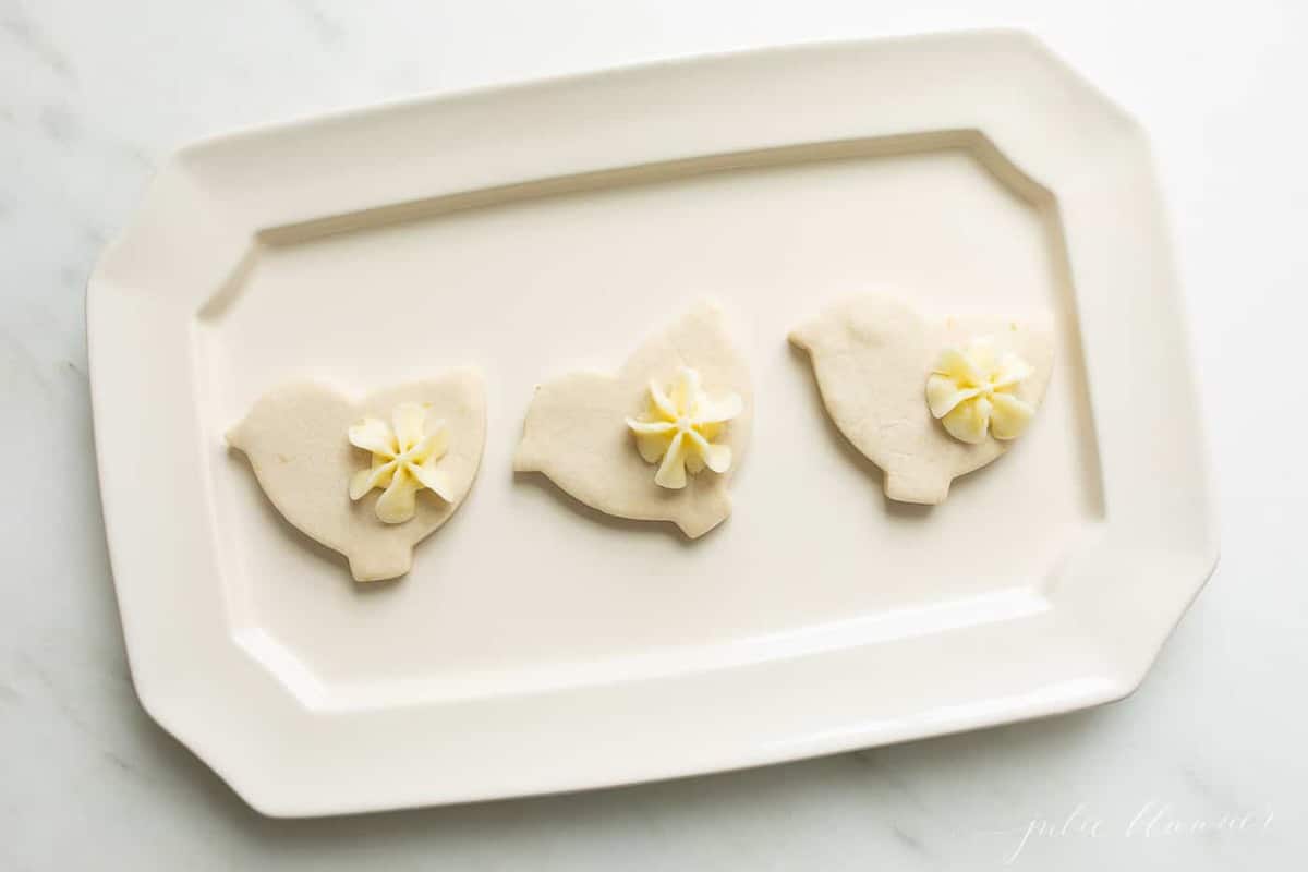 A white platter with three lemon cookies cutout as ducks.