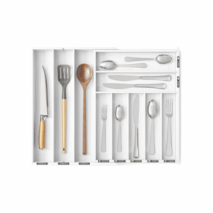 A kitchen drawer organizer with compartments and handy drawer dividers holds various utensils, including a carving knife, spatula, wooden spoon, serving spoons, table knives, forks, and spoons.