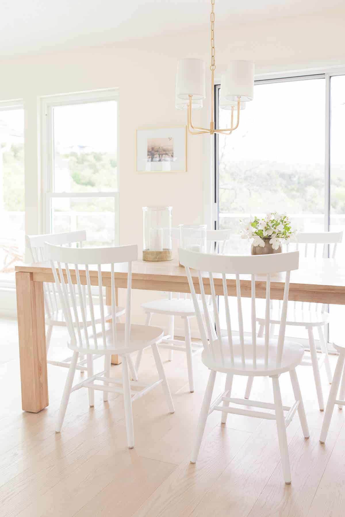 eat in kitchen with teak table white chairs and gold chandelier