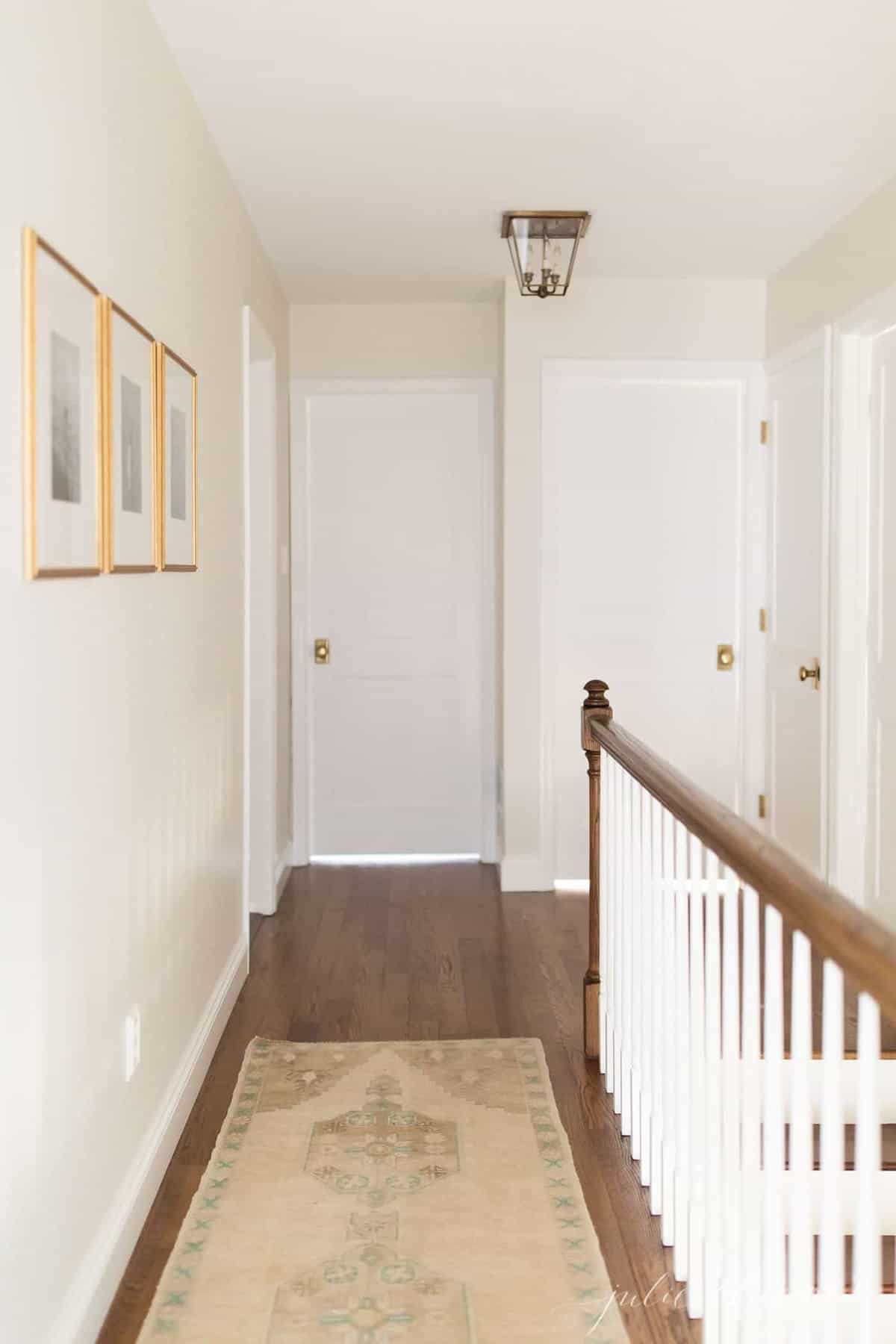 A white upstairs hallway in a home with a turkish rug on the floor.