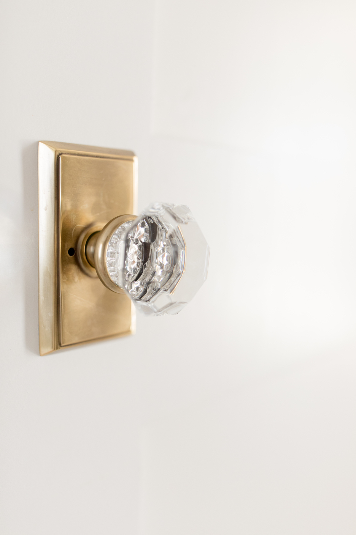 A brass and glass door knob on a white door