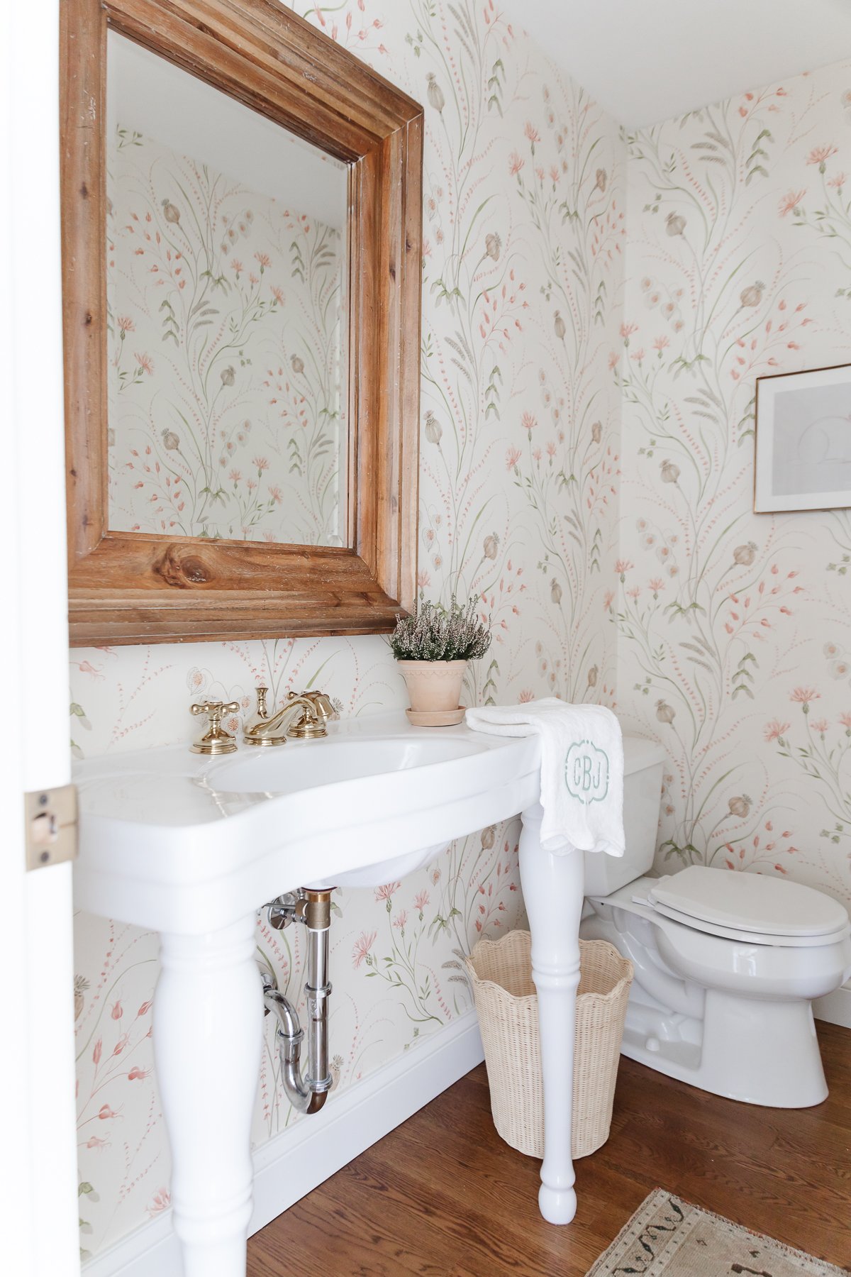 A wallpapered bathroom with a white pedestal sink
