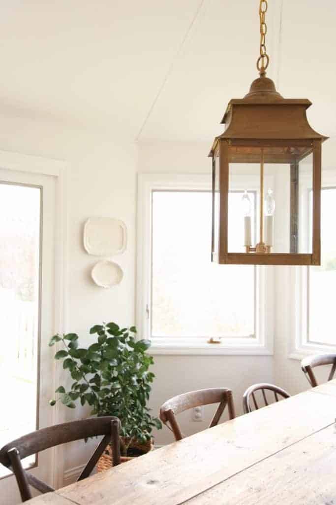 A brass lantern hanging in a white dining room in a character home.