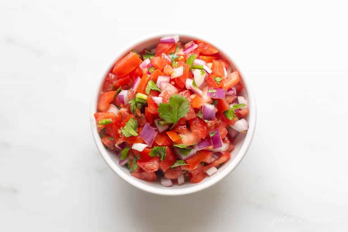 A white bowl filled with fresh pico de gallo.