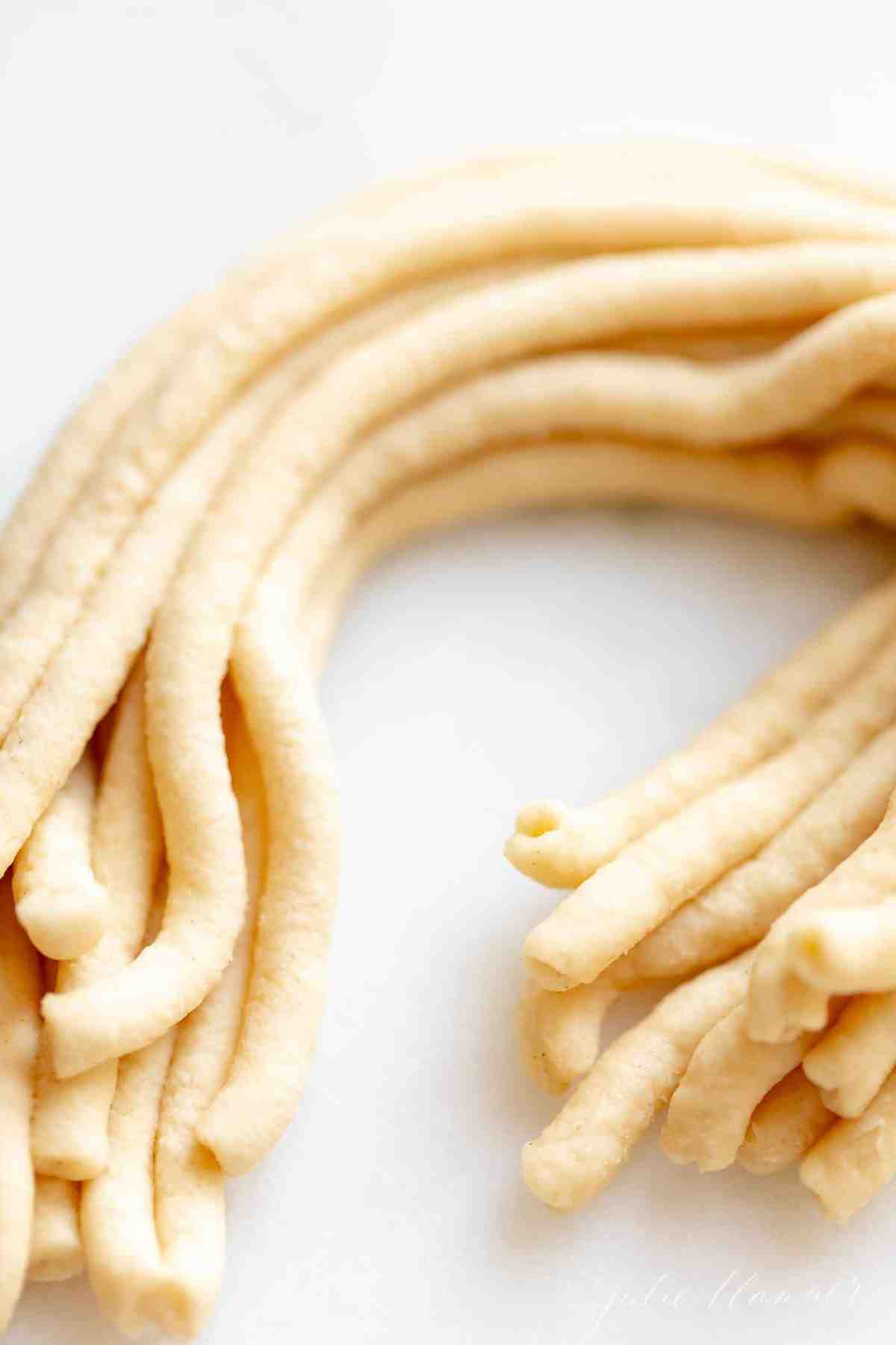 Homemade Bucatini pasta on a white surface.