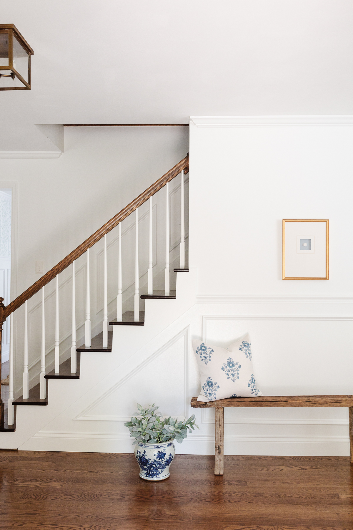 An entryway with a wood bench and picture frame moulding