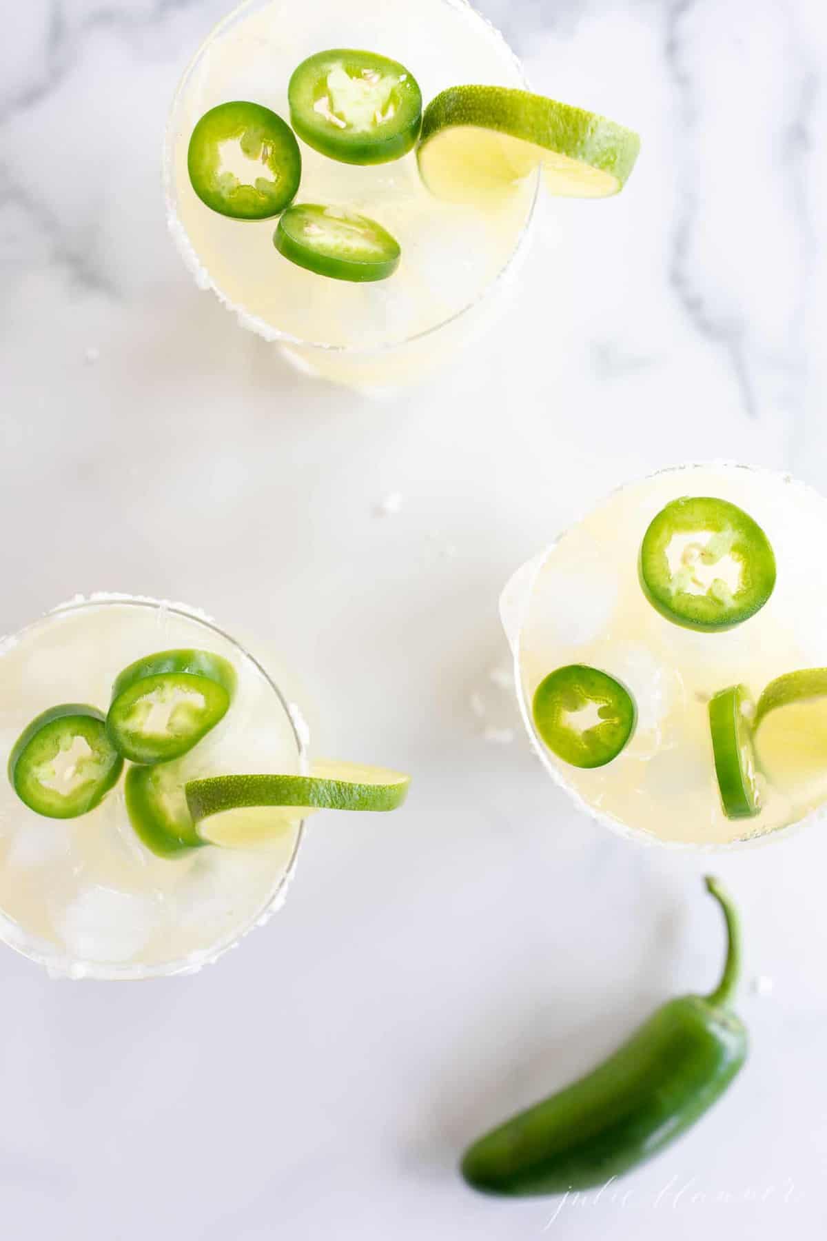Marble surface, three glasses full of jalapeno margaritas.