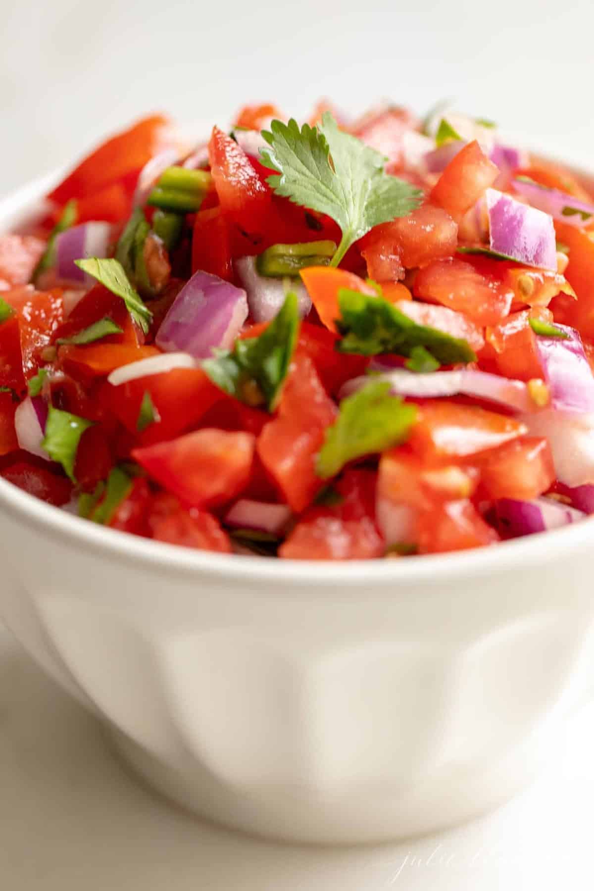 A white bowl filled with fresh pico de gallo.