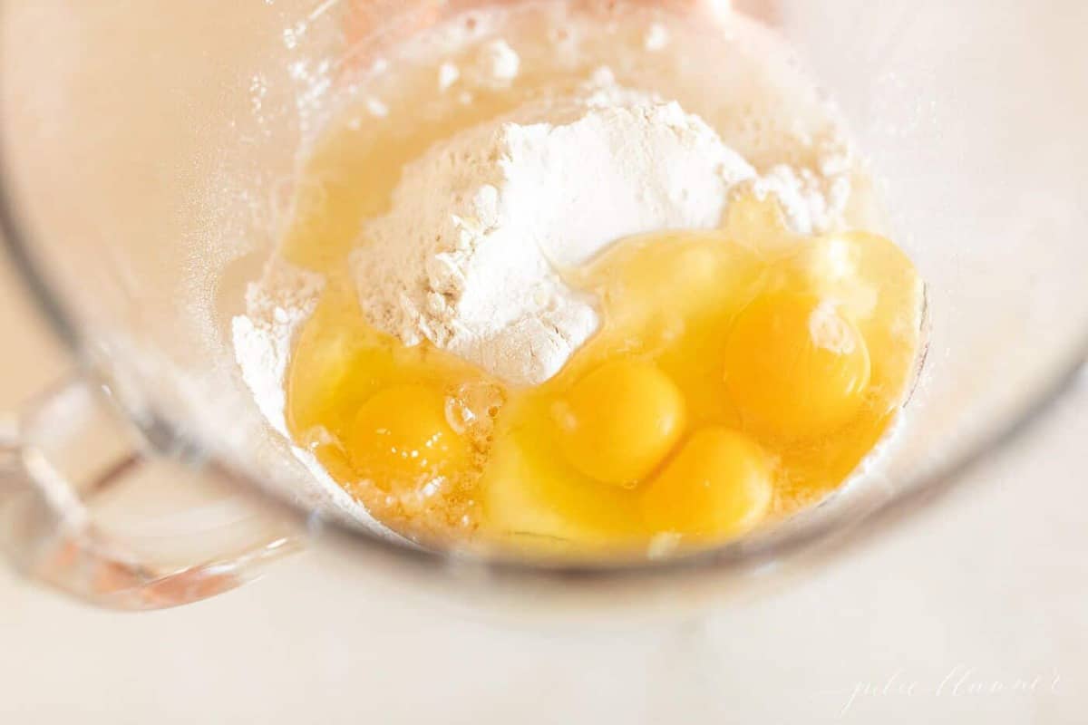 A mixing bowl with eggs and flour inside.