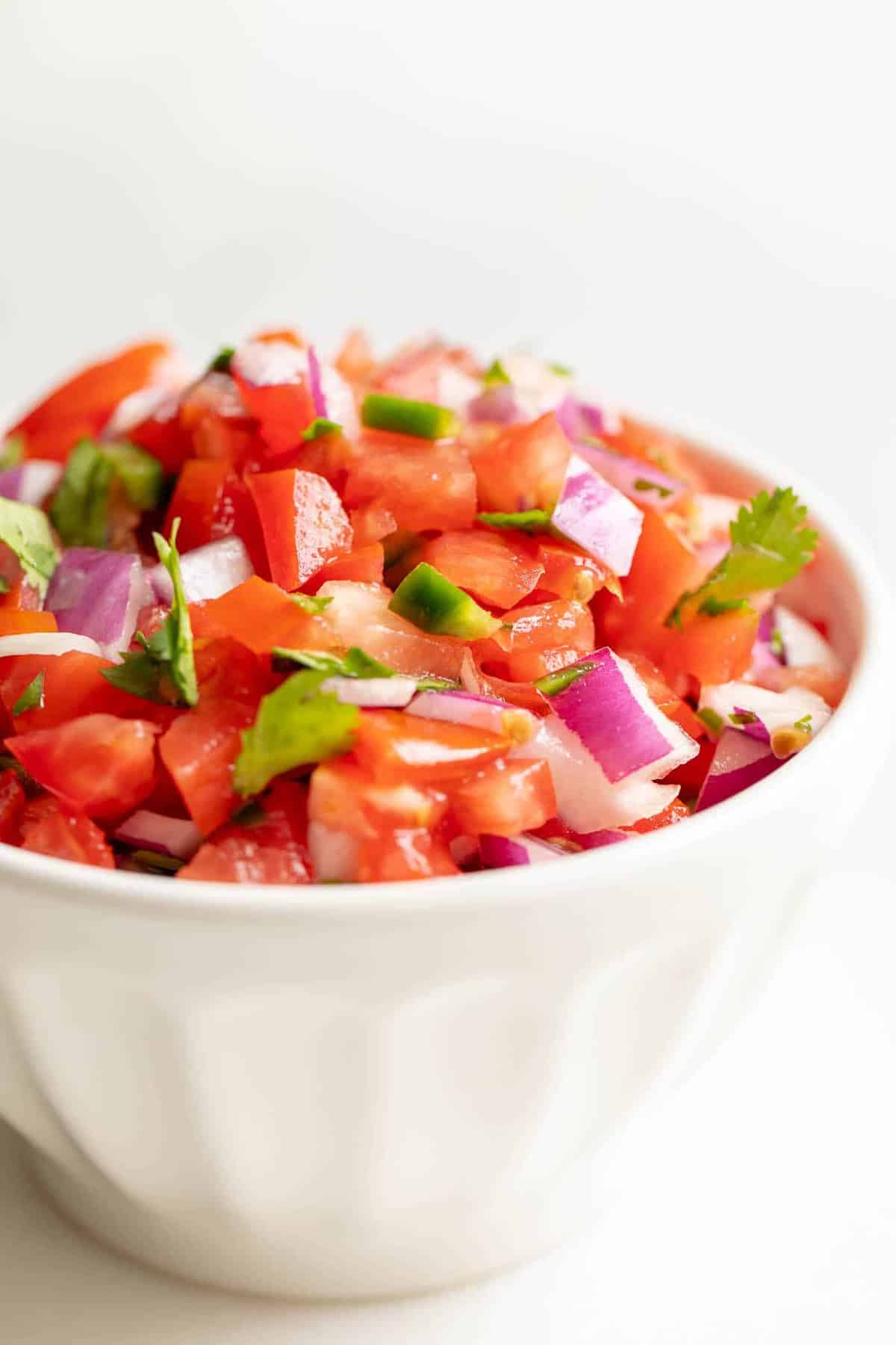 A white bowl filled with fresh pico de gallo.