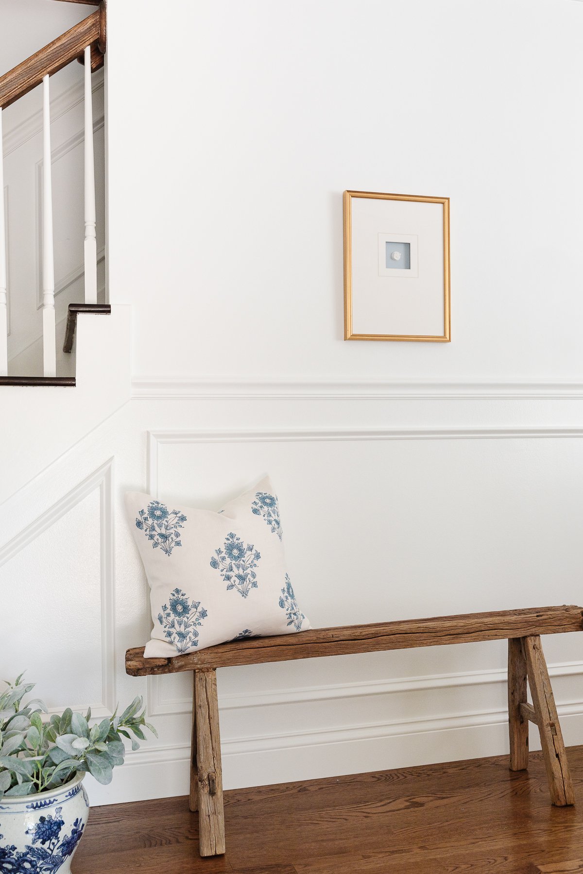 An entryway with a wood bench and picture frame moulding