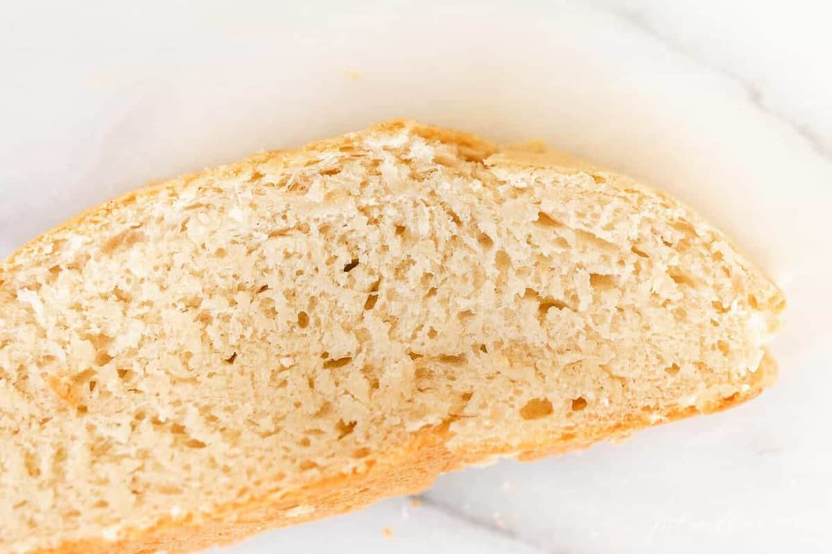 A slice of homemade bread made with rapid rise yeast on a marble surface.
