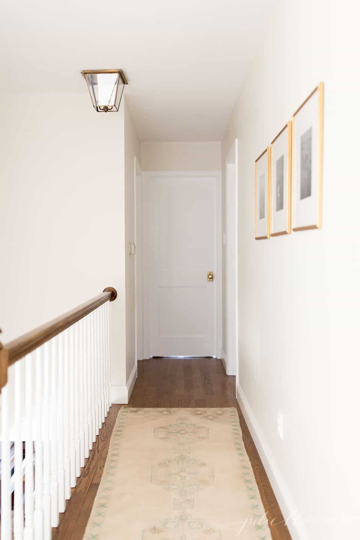A white upstairs hallway in a home with a turkish rug on the floor.