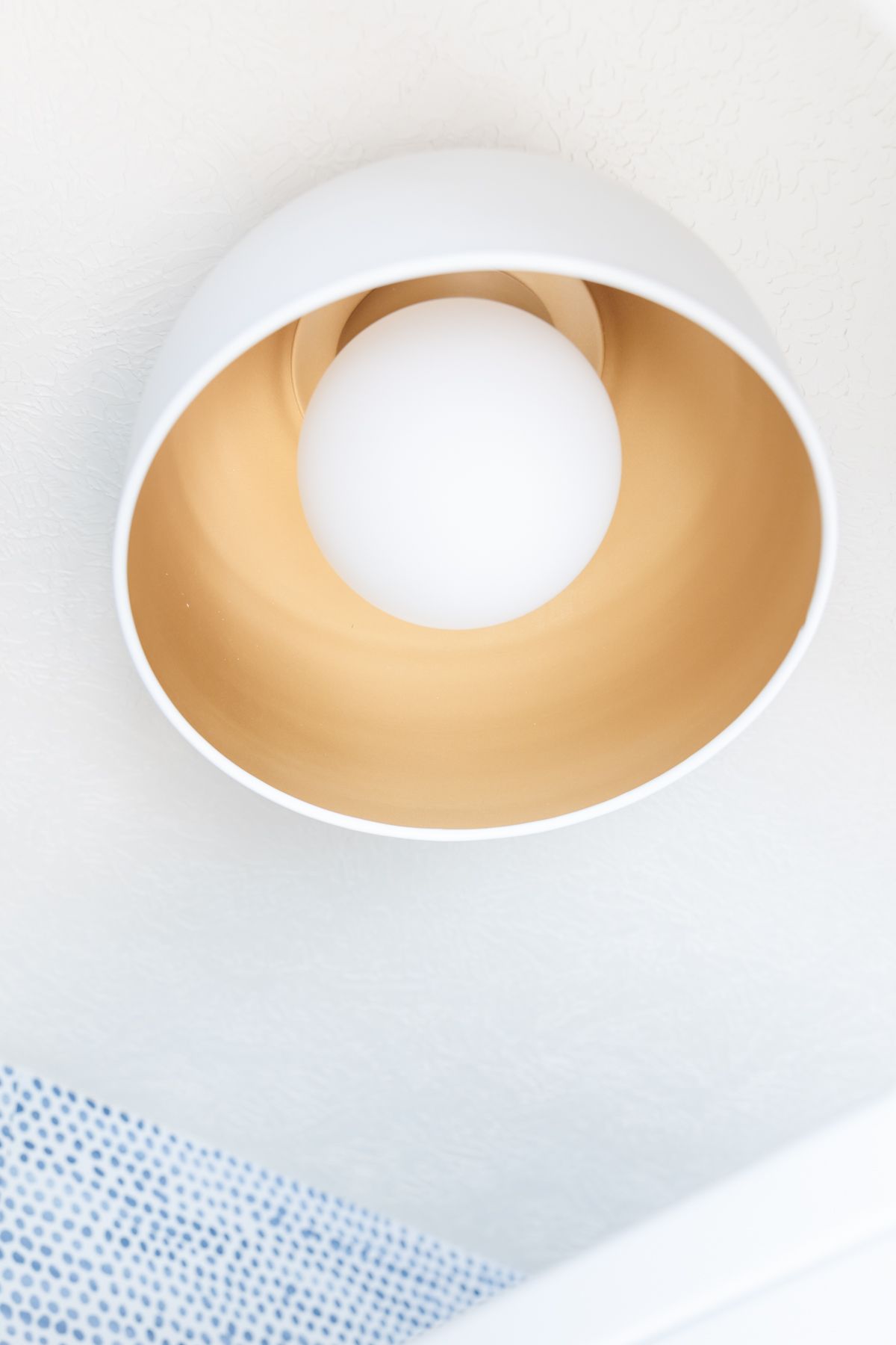 A flush mount light fixture with a gold interior and large white light bulb.