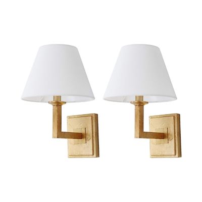 A pair of gold sconces with white shades