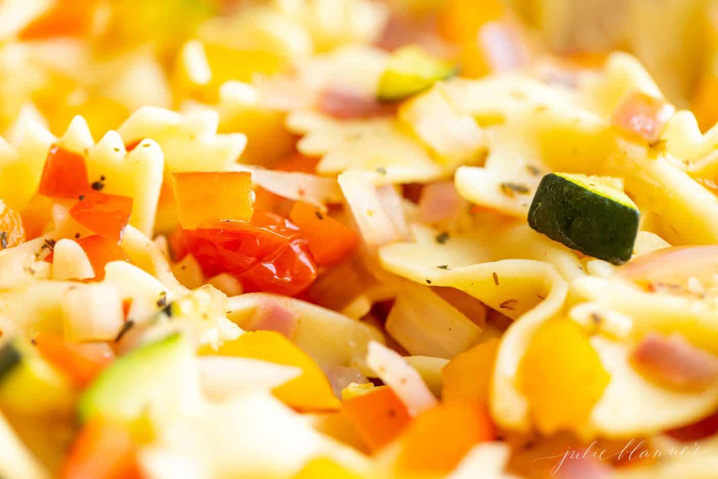 A white bowl filled with a fresh vegetarian pasta salad.