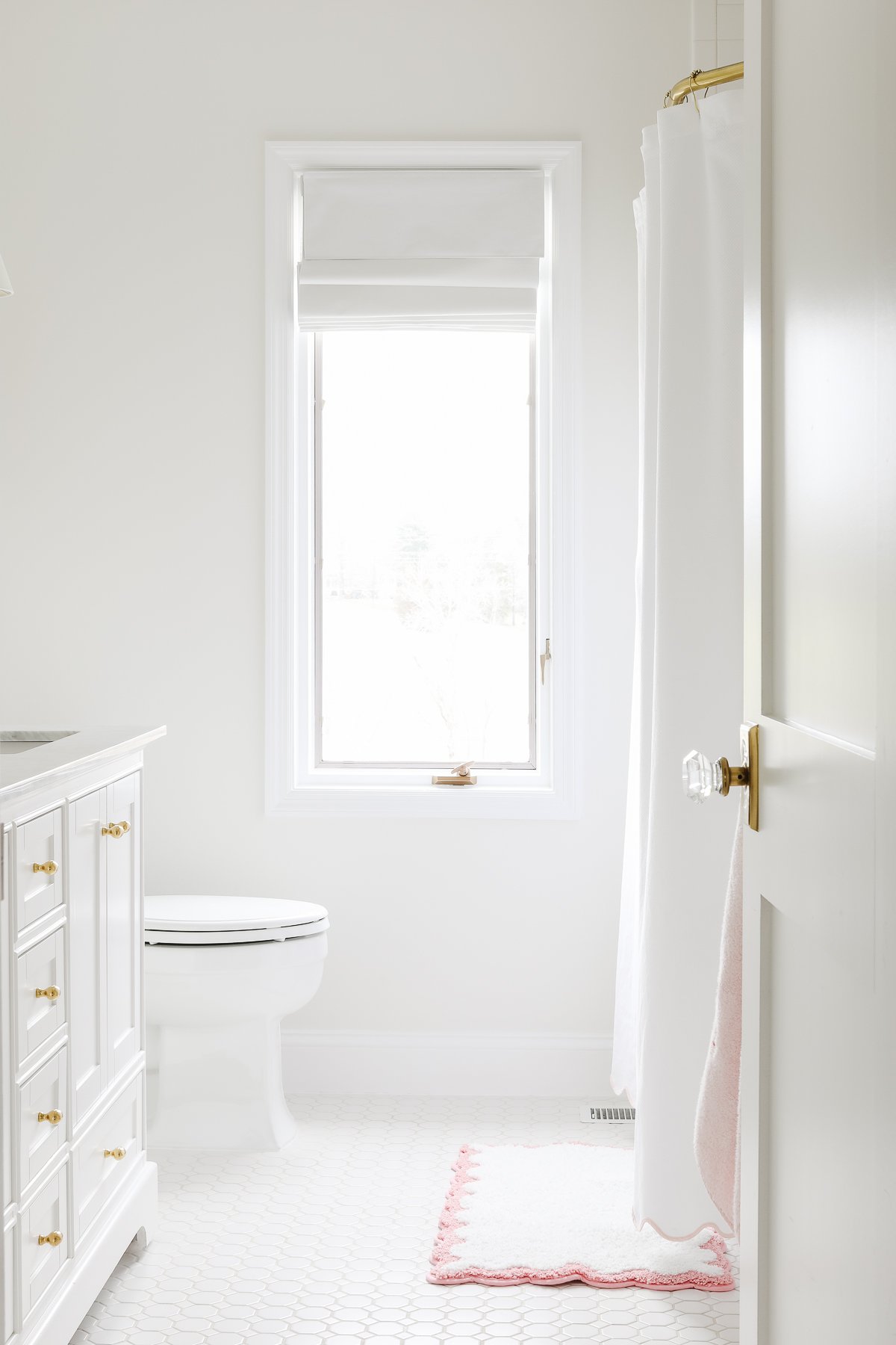 A white bathroom with gold fixtures and a Benjamin Moore White Dove trim.
