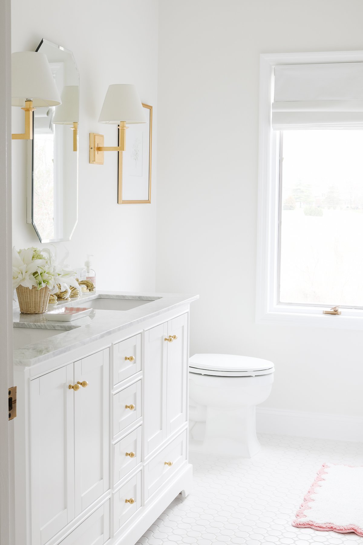 A white dove bathroom with gold accents and a window.