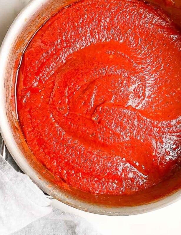 A silver sauce pan filled with homemade pizza sauce.