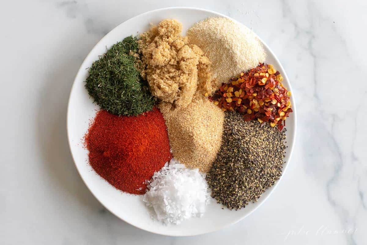 A white plate full of individual piles of seasonings and spices for a steak seasoning recipe blend.