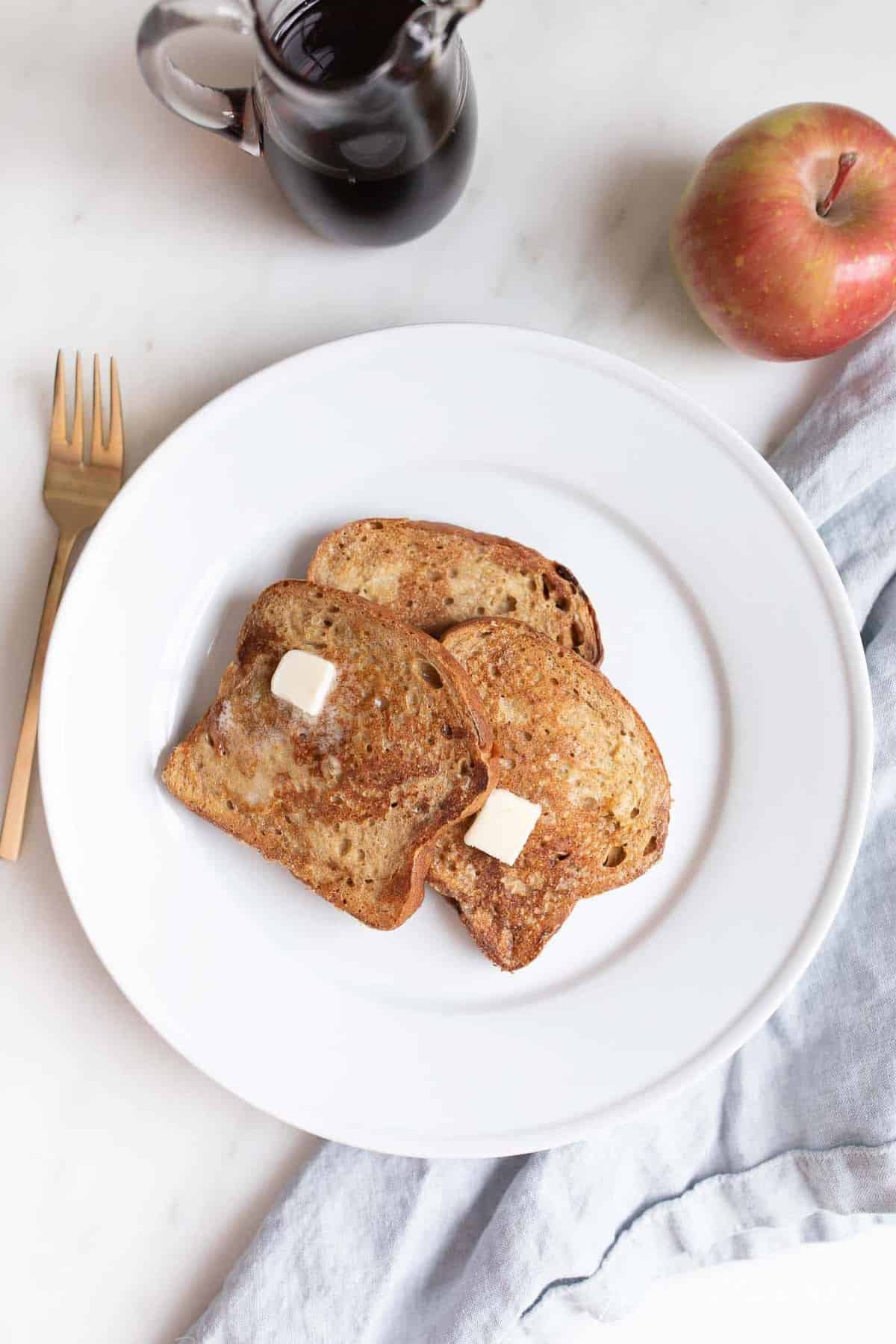 A white plate with slices of apple fritter french bread.