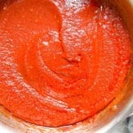 A silver sauce pan filled with homemade pizza sauce.