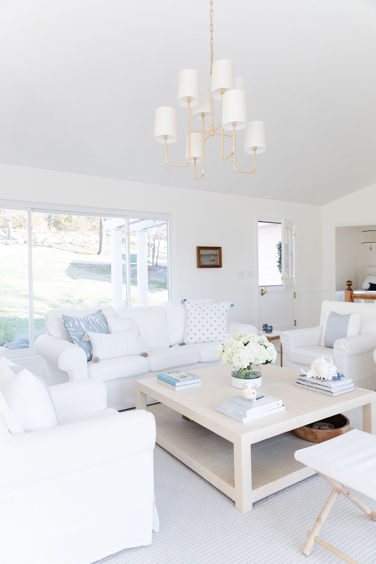 A warm white living room with a blue Dutch door and a brass chandelier