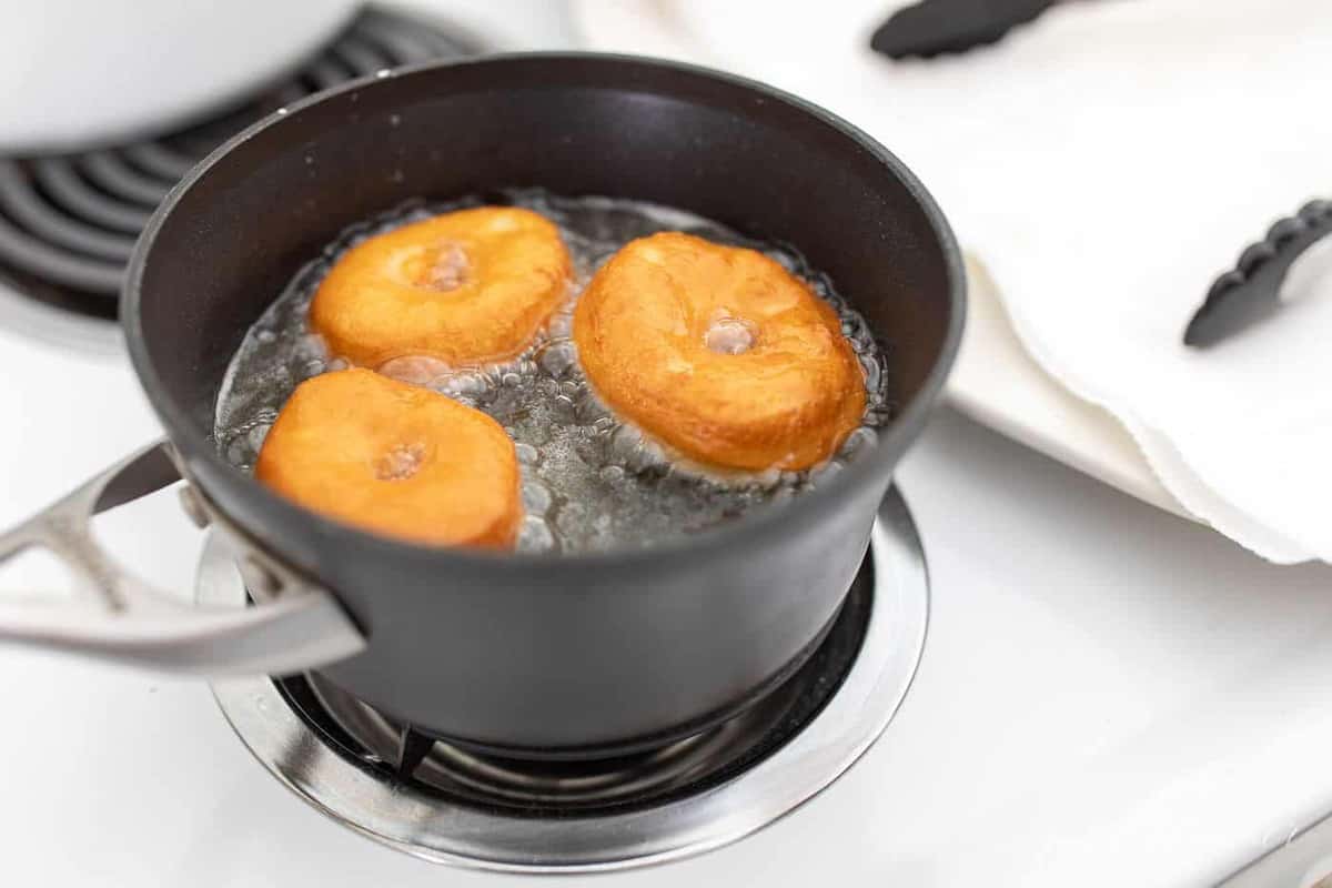 A sauce pan filled with oil frying easy homemade donuts.
