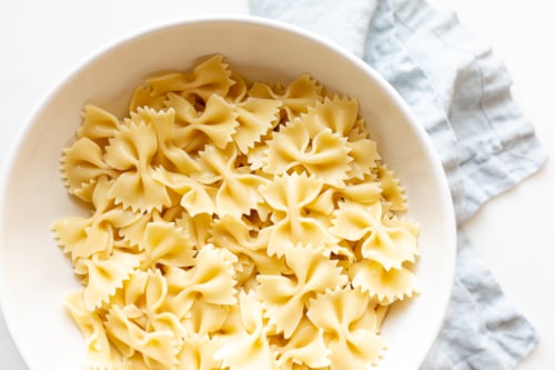 Cooked bow tie pasta in a white bowl.