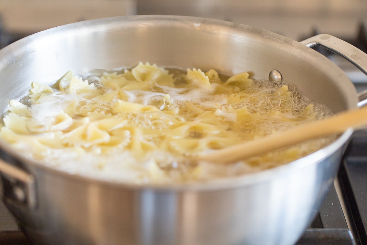 A stainless steel pot full of pasta in water on a stovetop