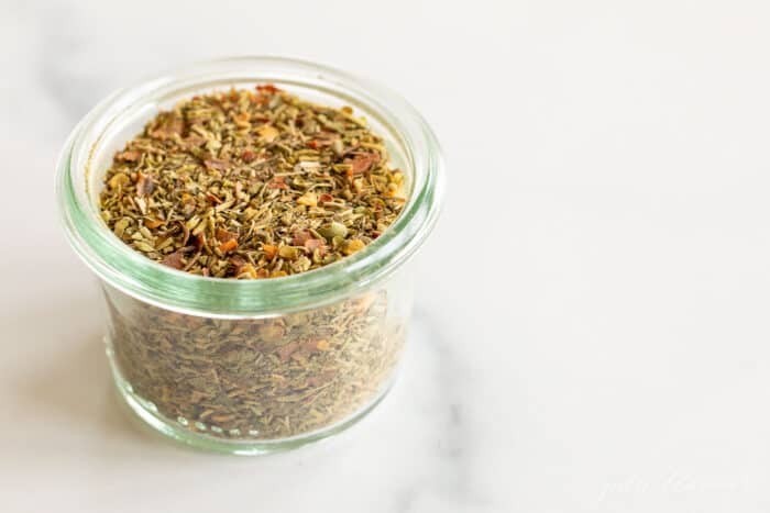 A clear glass jar of italian seasoning blend.