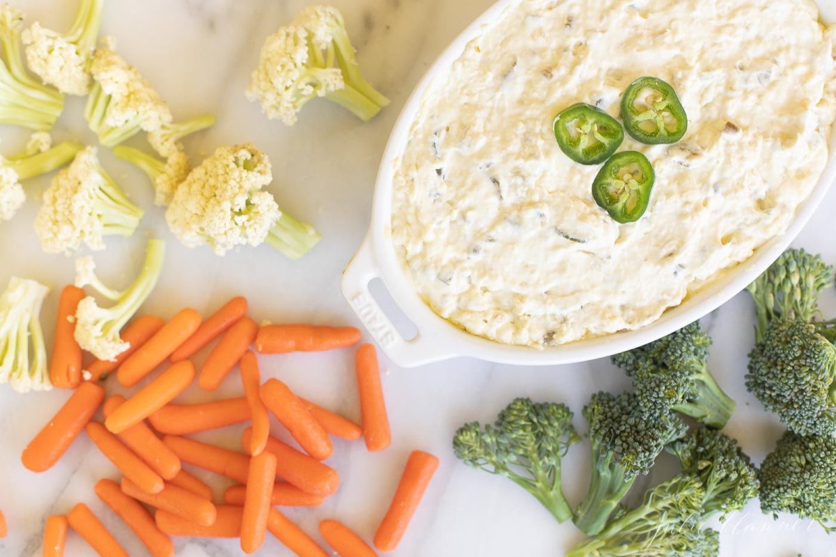 A creamy jalapeno dip surrounded by fresh vegetables for dipping.