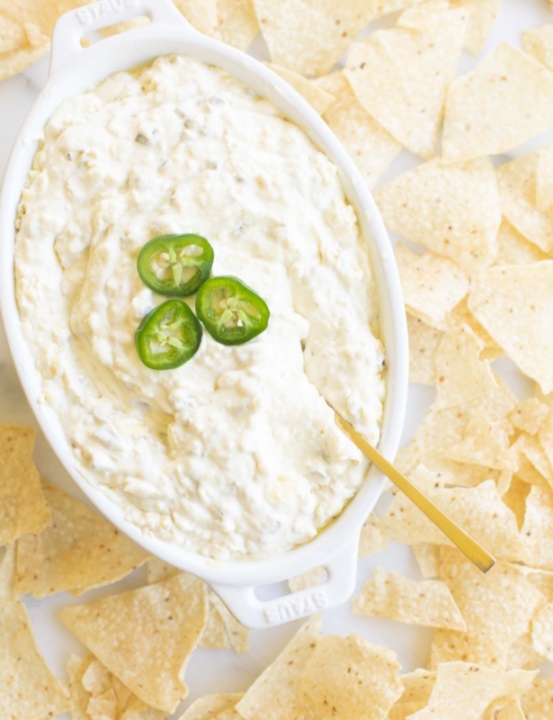 An oval serving dish full of jalapeno dip, surrounded by tortilla chips.