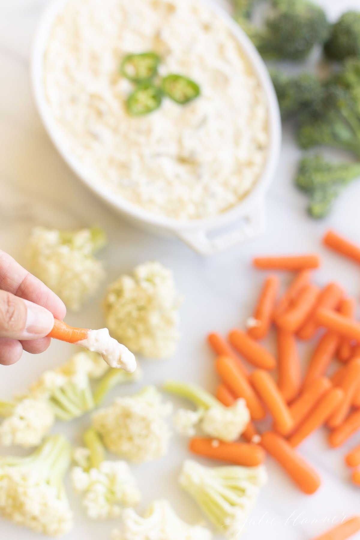 A creamy jalapeno dip surrounded by fresh vegetables for dipping.