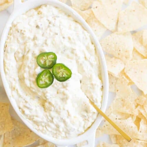 cheese dip with jalapeños on top and tortilla chips surrounding it