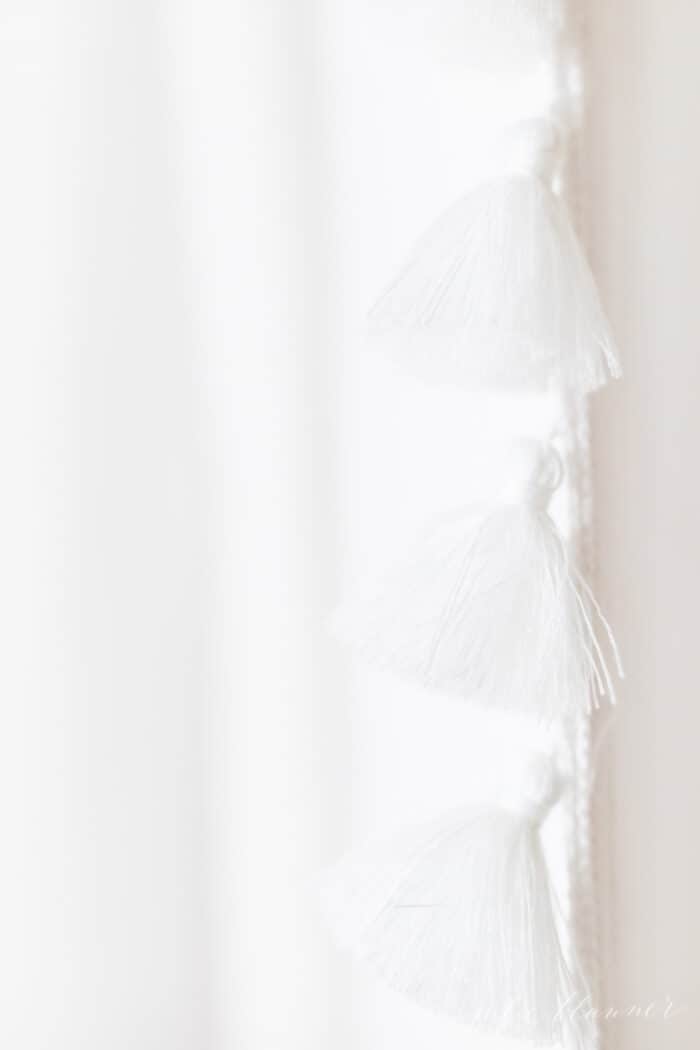 A white tasseled shower curtain in a bathroom update.