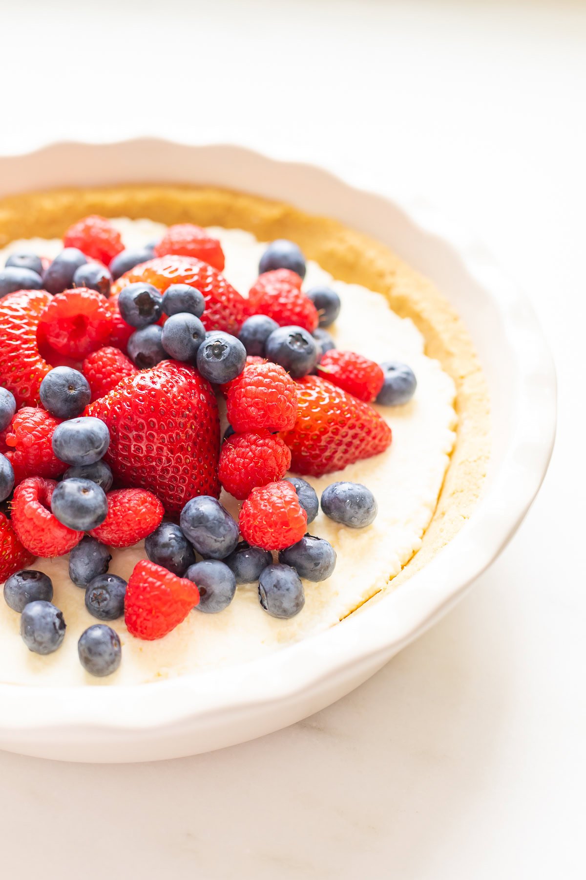 A no bake lemon pie topped with fresh strawberries, blueberries, and raspberries.