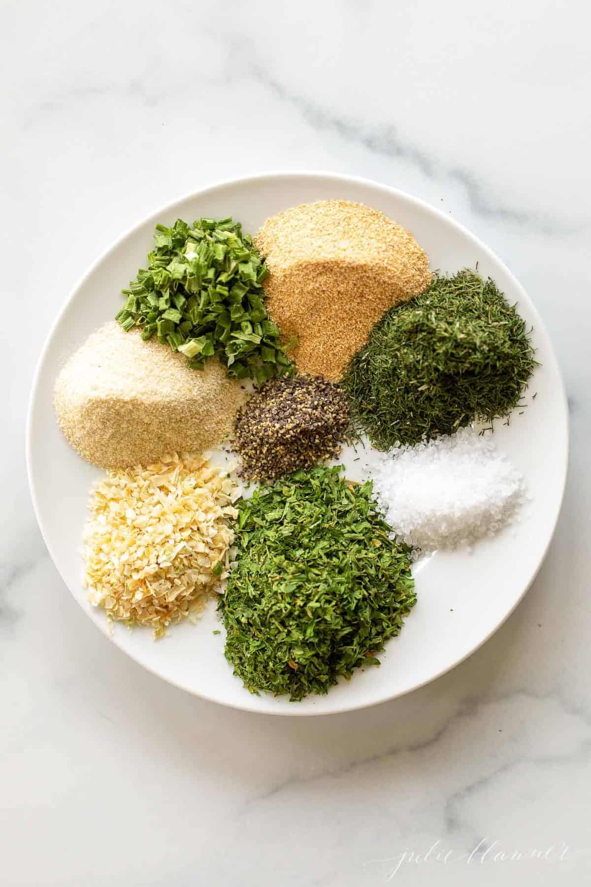 spices and herbs on a white plate on marble background