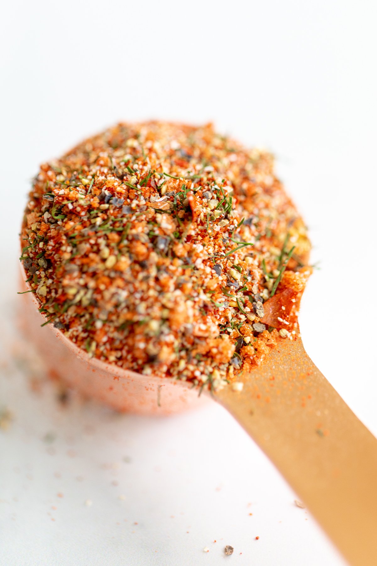 A spoon full of the best steak seasoning on a white surface.