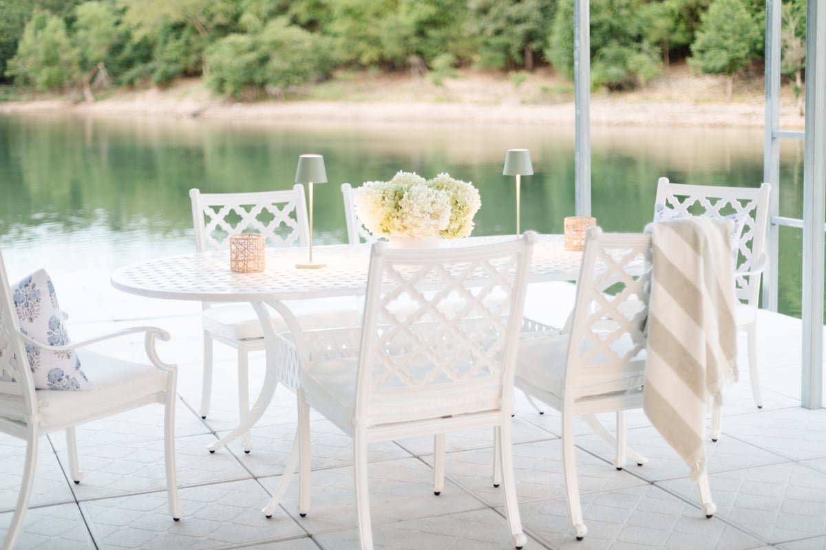 A white iron table set on a dock, water in the background