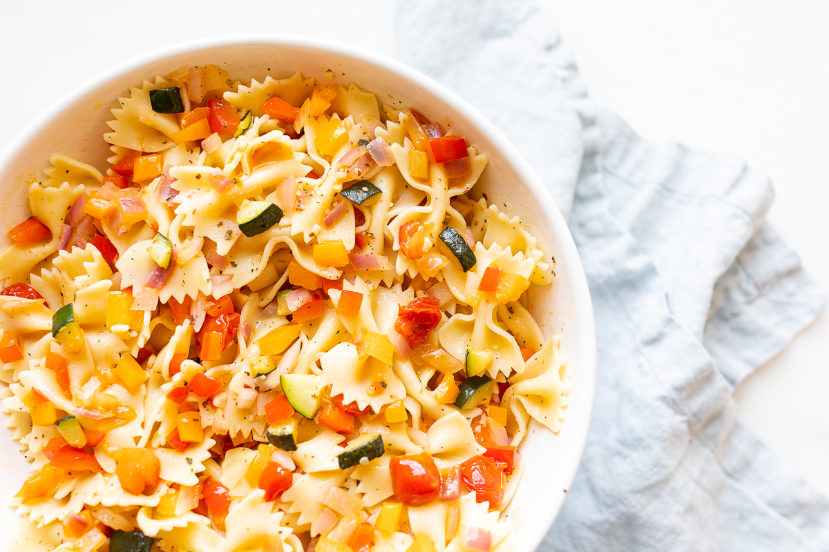 A white bowl full of veggie pasta salad.