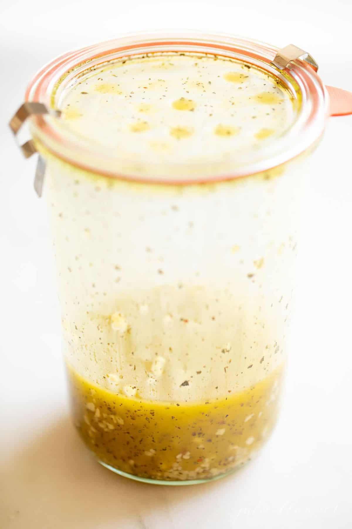 A glass jar filled with dressing for a vegetarian pasta salad recipe.